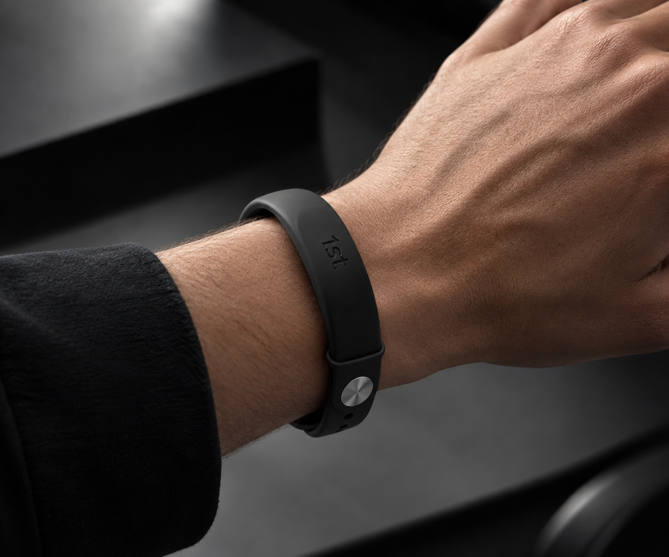 A black 1st band with a brushed steel clasp worn on the wrist